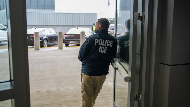 A U.S. Immigration and Customs Enforcement (ICE) agent stands at John F. Kennedy International...