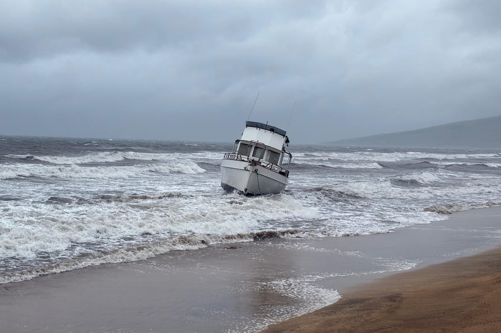 En esta foto proporcionada por el condado Maui, un barco está encallado en una playa frente a...