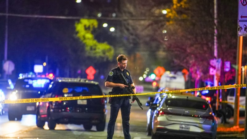 An Austin police officer guards the scene on West 6th Street at West Avenue after a shooting,...