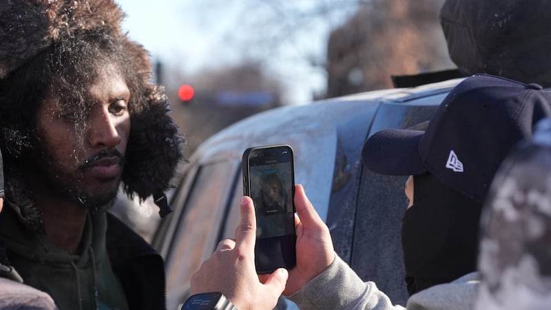 Agentes federales utilizan una app de reconocimiento facial con una personas detenida, que...