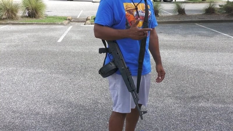 Un hombre que portaba un fusil AK-47 a la vista caminó cerca del campus de la Universidad de...